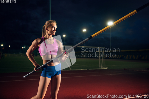 Image of Female pole vaulter training at the stadium in the evening