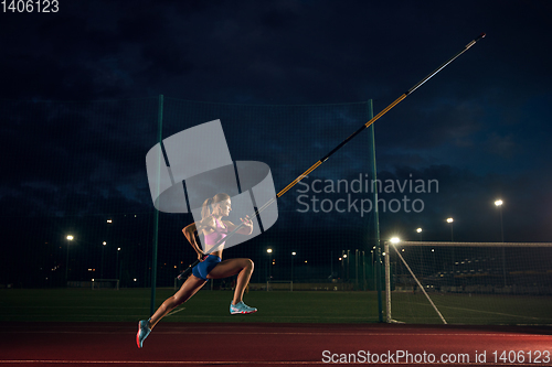 Image of Female pole vaulter training at the stadium in the evening