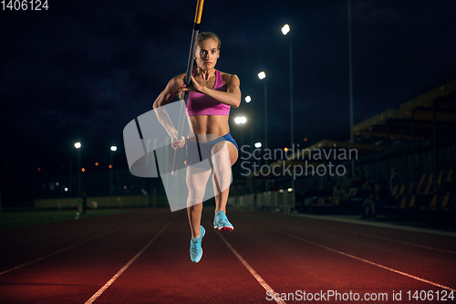 Image of Female pole vaulter training at the stadium in the evening