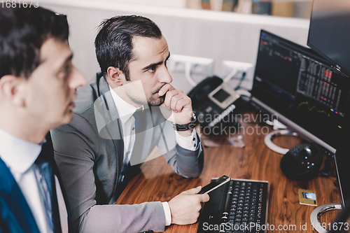 Image of Stock brokers looking at computer screens, trading online.