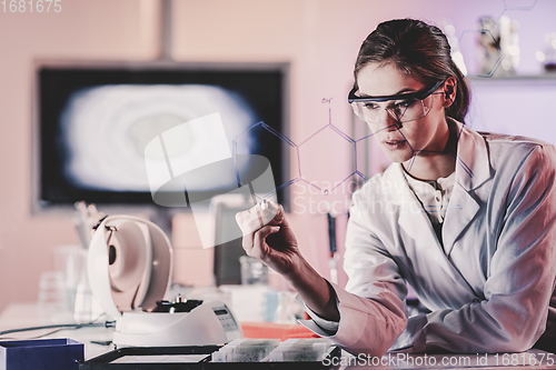 Image of Portrait of a confident female researcher in life science laboratory writing structural chemical formula on a glass board.