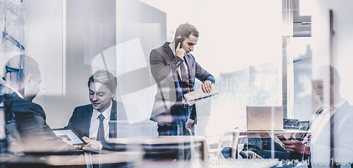 Image of Businessman talking on a mobile phone on corporate office.