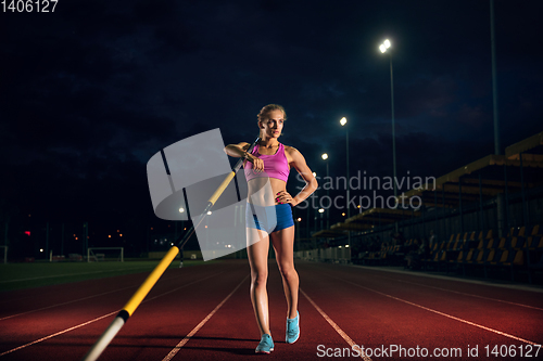 Image of Female pole vaulter training at the stadium in the evening