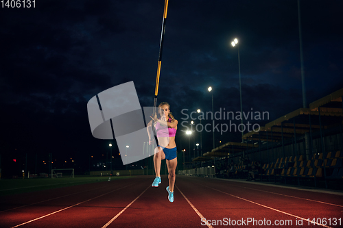 Image of Female pole vaulter training at the stadium in the evening