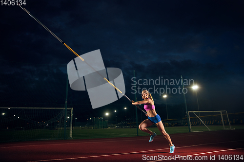 Image of Female pole vaulter training at the stadium in the evening