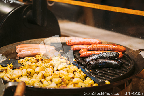 Image of Frying Potatoes And Sausages - A Traditional Christmas Dish Of Street Food On Streets Of Europe In Winter During The Christmas Holidays