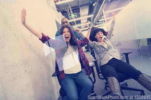 Image of multiethnics business team racing on office chairs