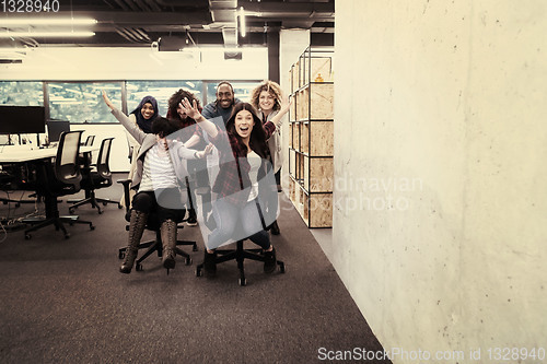 Image of multiethnics business team racing on office chairs