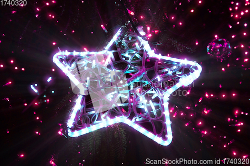 Image of Bright beautiful glowing star on a Christmas tree in the evening