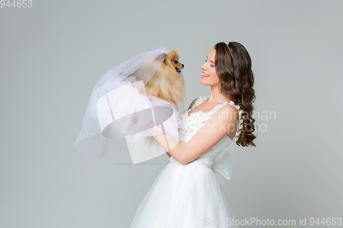 Image of beautiful bride girl with spitz bride on gray background