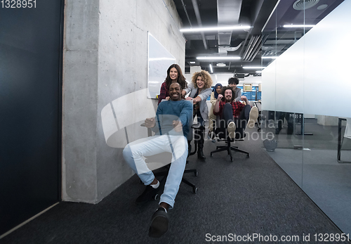 Image of multiethnics business team racing on office chairs