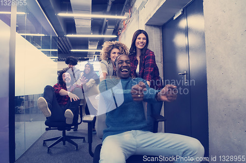 Image of multiethnics business team racing on office chairs