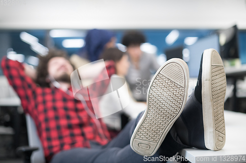 Image of software developer resting with legs on desk