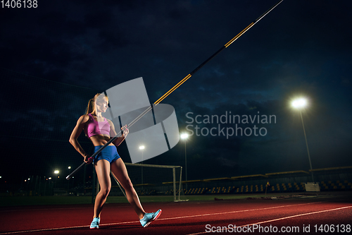 Image of Female pole vaulter training at the stadium in the evening