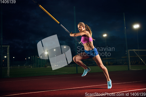 Image of Female pole vaulter training at the stadium in the evening