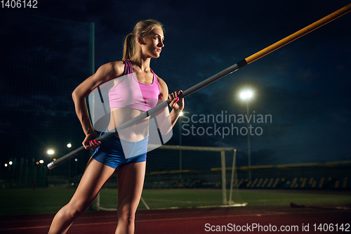 Image of Female pole vaulter training at the stadium in the evening