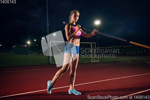 Image of Female pole vaulter training at the stadium in the evening