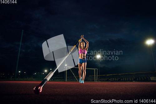 Image of Female pole vaulter training at the stadium in the evening