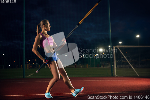 Image of Female pole vaulter training at the stadium in the evening