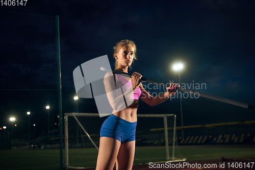 Image of Female pole vaulter training at the stadium in the evening