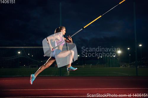 Image of Female pole vaulter training at the stadium in the evening