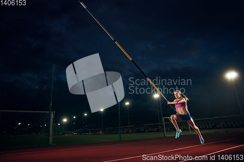 Image of Female pole vaulter training at the stadium in the evening