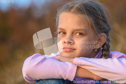 Image of Portrait of a thoughtful beautiful ten-year-old girl at sunset