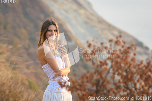 Image of Beautiful girl in a white dress on a background of mountains