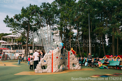 Image of Batumi, Adjara, Georgia. Children and adults play on playground on city street near waterfront.