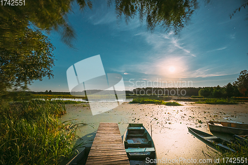 Image of Real Night Sky Stars And Moonrise Above Old Pier With Moored Wooden Fishing Boat. Natural Starry Sky And Countryside Landscape With Lake River In Early Spring Night. Russian Nature