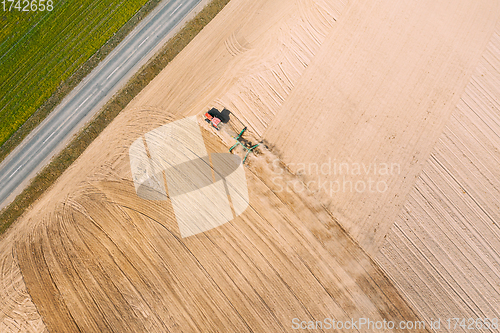 Image of Aerial View. Tractor Plowing Field. Beginning Of Agricultural Spring Season. Cultivator Pulled By A Tractor In Countryside Rural Field Landscape. Dust Rises From Under Plows