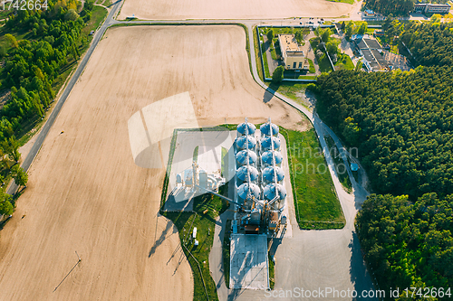 Image of Aerial View Modern Granary, Grain-drying Complex, Commercial Grain Or Seed Silos In Sunny Spring Rural Landscape. Corn Dryer Silos, Inland Grain Terminal, Grain Elevators Standing In A Field