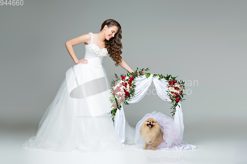 Image of bride girl with dog bride under flower arch