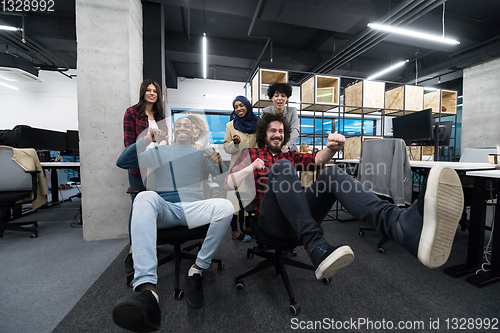 Image of multiethnics business team racing on office chairs