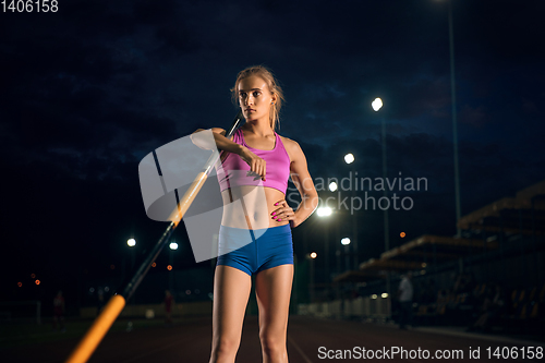 Image of Female pole vaulter training at the stadium in the evening