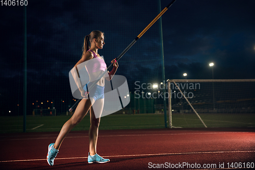 Image of Female pole vaulter training at the stadium in the evening