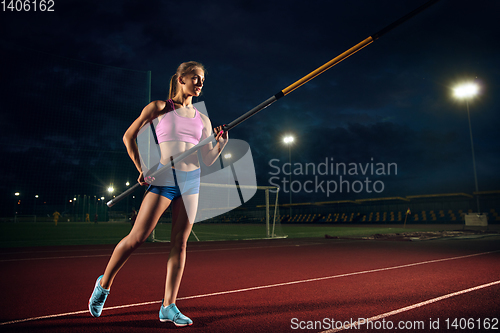 Image of Female pole vaulter training at the stadium in the evening