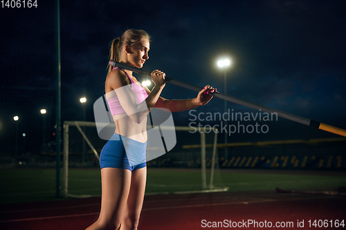 Image of Female pole vaulter training at the stadium in the evening