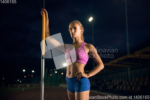 Image of Female pole vaulter training at the stadium in the evening