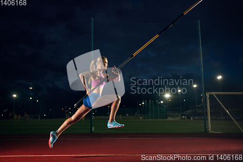 Image of Female pole vaulter training at the stadium in the evening