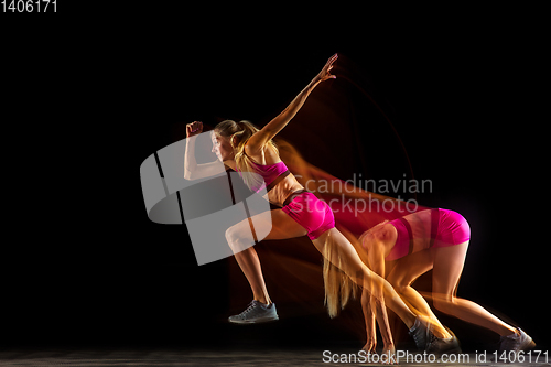 Image of Professional female relay racer training on black studio background in mixed light