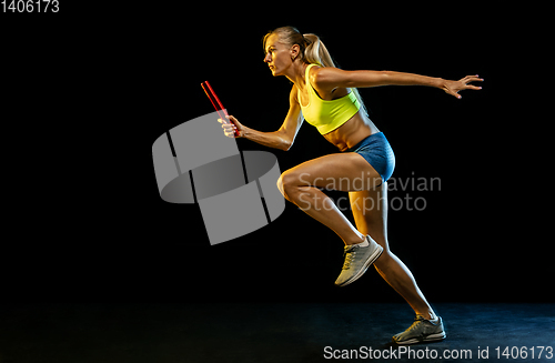 Image of Professional female relay racer training on black studio background in neon light