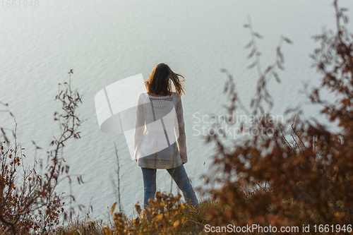 Image of Slender girl standing on the seashore, rear view