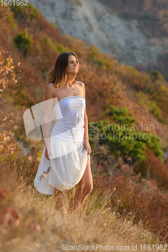 Image of beautiful girl in white dress walking on the mountainside