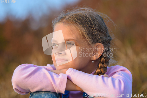 Image of Portrait of a beautiful ten-year-old girl looking at the sunset, close-up