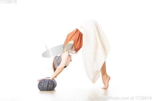 Image of Restorative yoga with a bolster. Young sporty attractive woman in bright white yoga studio, stretching and relaxing during restorative yoga with bolster cushion. Healthy active lifestyle