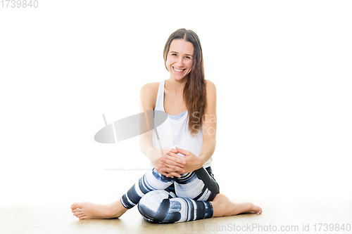 Image of Young sporty female yoga instructor in bright white yoga studio, smiling cheerfully, looking at the camera.
