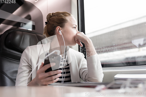 Image of Businesswoman communicating on mobile phone while traveling by train.