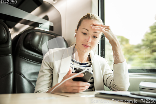 Image of Businesswoman communicating on mobile phone while traveling by train.