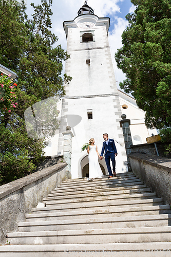 Image of The Kiss. Bride and groom kisses tenderly on a staircase in front of a small local church.